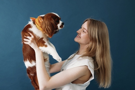 Side view of young woman holding her little dog in studio