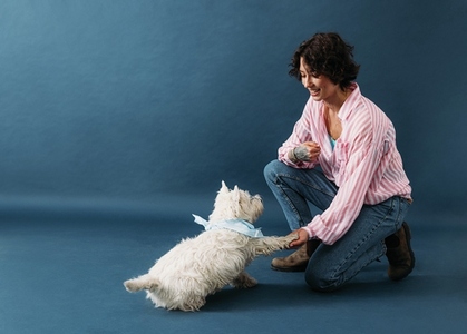 Woman shaking paw of cute dog  Young female kneeling as she holds the paw of a little white dog