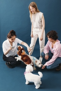 Young females and their dogs playing together in studio