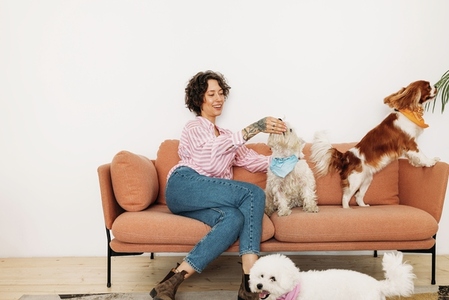 Young woman sitting on a couch with three dogs in living room