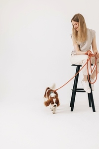 Young woman sitting on chair with dog leash and pet