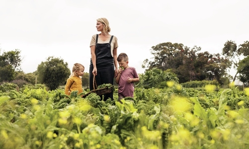 Mother standing in a vegetable garden with her children