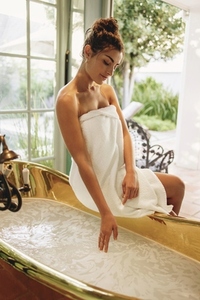 Attractive young woman preparing a bath in a luxury hotel