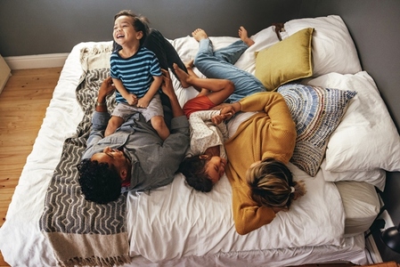 Parents playing with their children on the bed