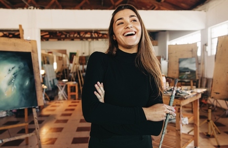 Artistic entrepreneur laughing cheerfully in her workshop
