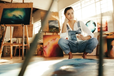 Freelance painter holding a cup of coffee in her art studio