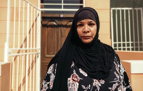 Confident Muslim woman looking at the camera outside her home