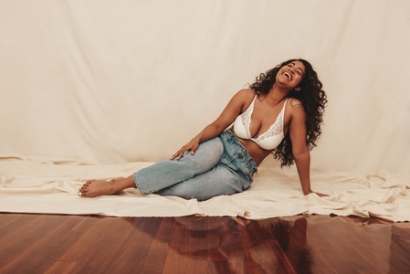 Carefree young woman laughing while sitting on the studio floor
