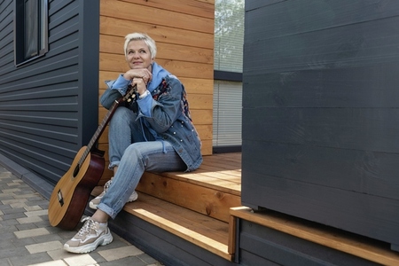 Happy woman with guitar on front stoop
