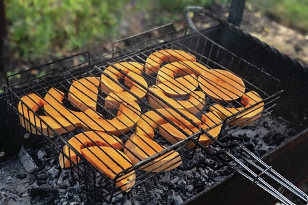 Butternut squash slices cooking on barbecue grill