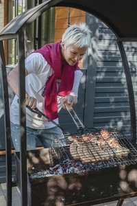 Woman cooking sausages on barbecue grill