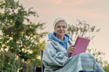 Portrait woman using digital tablet in backyard
