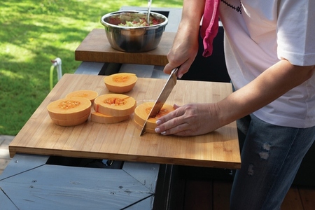 Woman slicing fresh butternut squash on patio