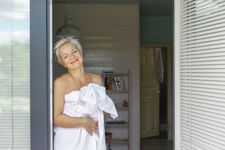 Carefree woman wrapped in sheet at bedroom doorway
