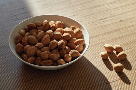 Sunlight over bowl of almonds in shell