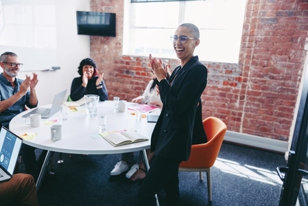 Young businesswoman being applauded by her team in an office