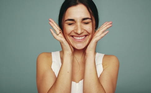 Excited young woman smiling with her eyes closed in a studio