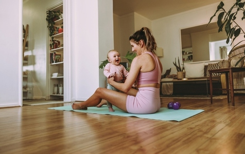 Happy mom working out with her baby at home