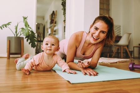 Cheerful mom doing plan exercises with her baby at home