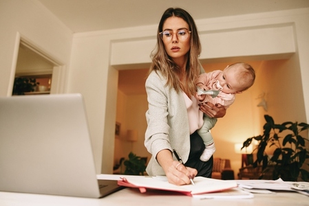 Design professional making notes while holding her baby