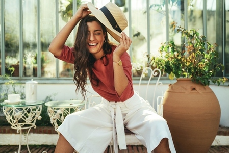 Happy young woman holding a summer hat