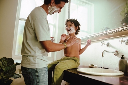 Playful father and son having fun with shaving foam