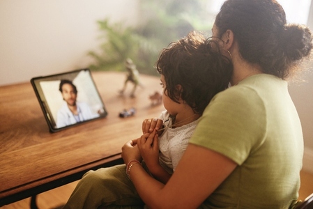 Mother and child video calling their family doctor at home