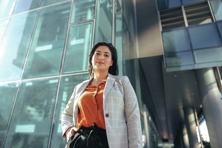 Confident businesswoman standing in front of an office building