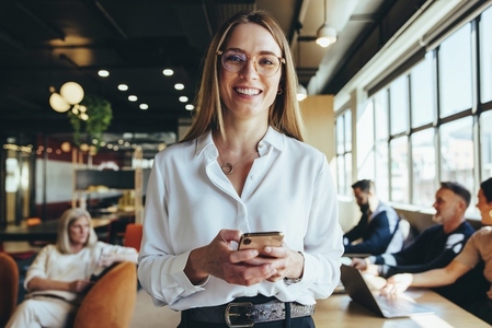 Young businesswoman holding a smartphone in a co working space