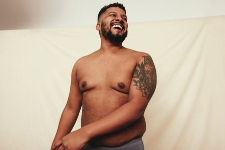 Tattooed man laughing cheerfully in a studio