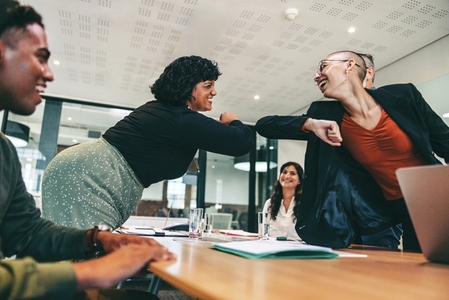 Smiling businesswomen elbow bumping each other before a meeting