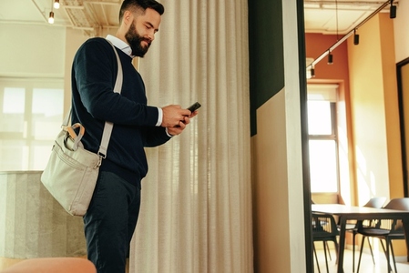 Cheerful businessman using a smartphone in a co working space