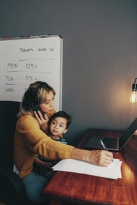 Busy mom writing notes during a business phone call