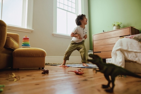 Playful young boy mimicking a t rex dinosaur at home