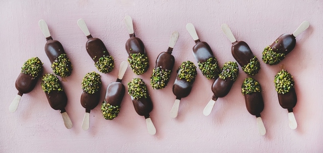 Flat lay of chocolate glazed ice cream pops with pistachio icing