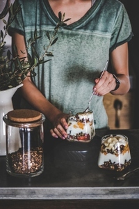 Woman having healthy breakfast with yogurt  granola  fruits in glass