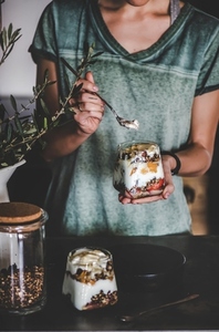 Woman having healthy vegan breakfast with yogurt in glass
