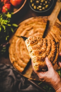 Human hands holding piece of Turkish borek with spinach filling