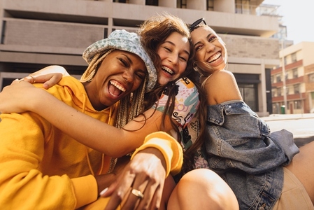 Three female friends laughing together outdoors