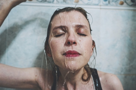 Artistic portrait of a young woman under shower water