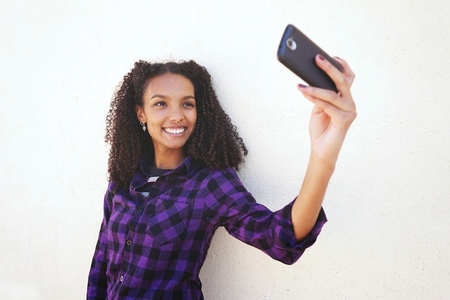 Young cool woman taking a self portrait with her mobile against