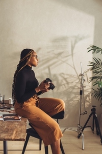 Female artist holding a dslr camera in her home office