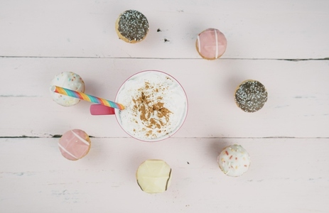 Cupcakes and delicious hot cocoa over a pink wooden background