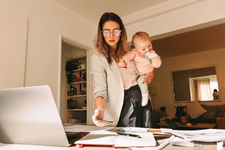 Female interior designer holding her baby in her home office