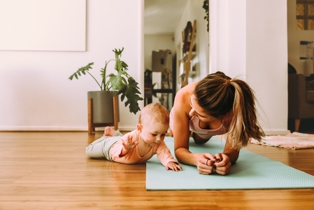 Mom doing plank exercises with her baby