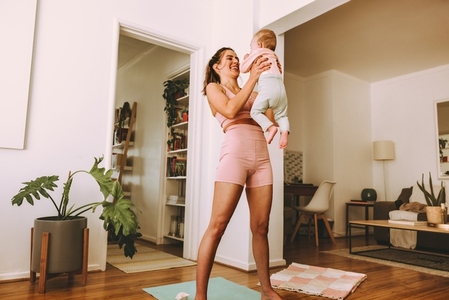 Cheerful mom lifting her baby at home