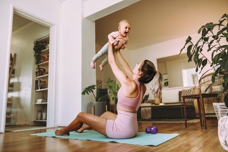 Playful mom lifting her adorable baby into the air