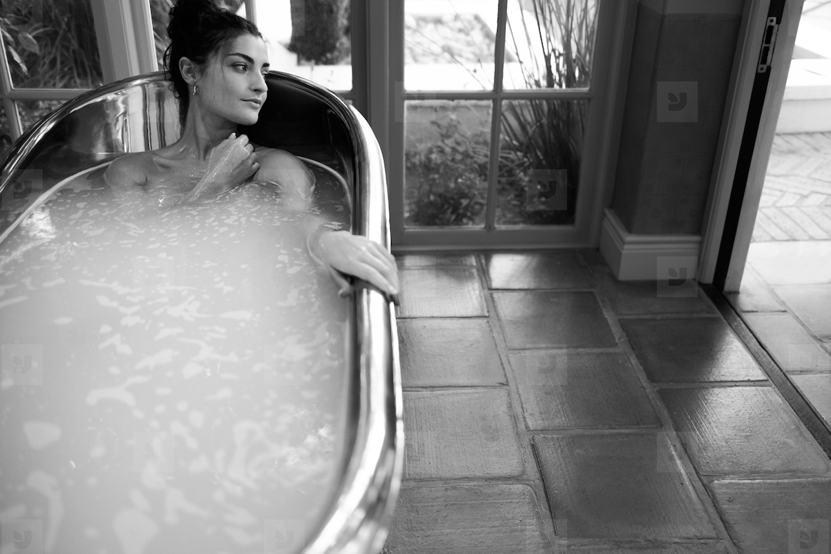 Black and white shot of a woman relaxing in a bathtub