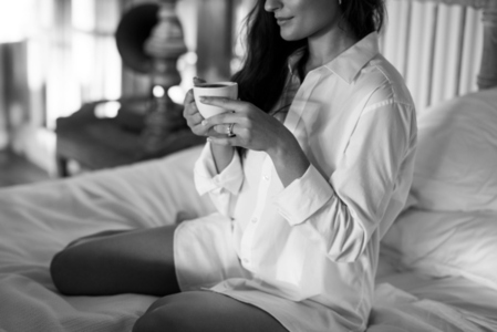 Brunette woman enjoying a cup of coffee in her hotel room