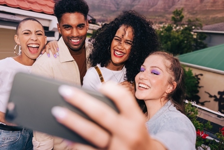 Friends smiling for a group selfie on a rooftop